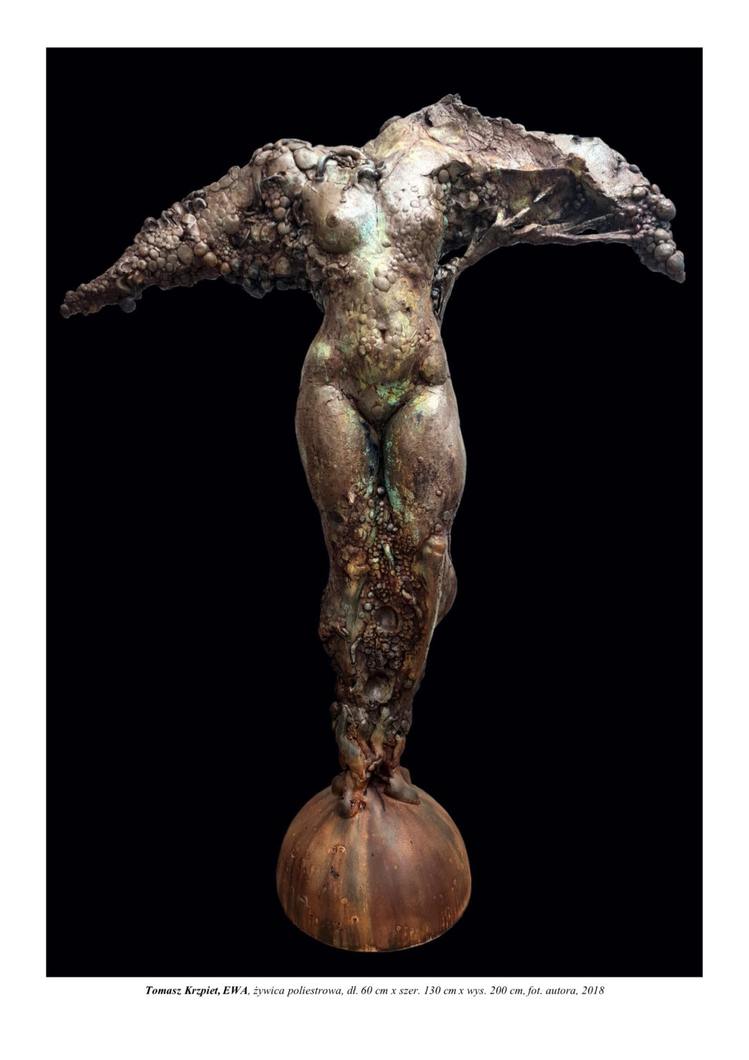 Rzeźba kobiety, biblijnej „Ewy”. Stoi na półkuli. Jej struktura tworzy się i narasta jak drzewo. Ma rozpostarte ręce, bez głowy. Kompozycja rzeźbiarska w kolorystyce barw ziemi.